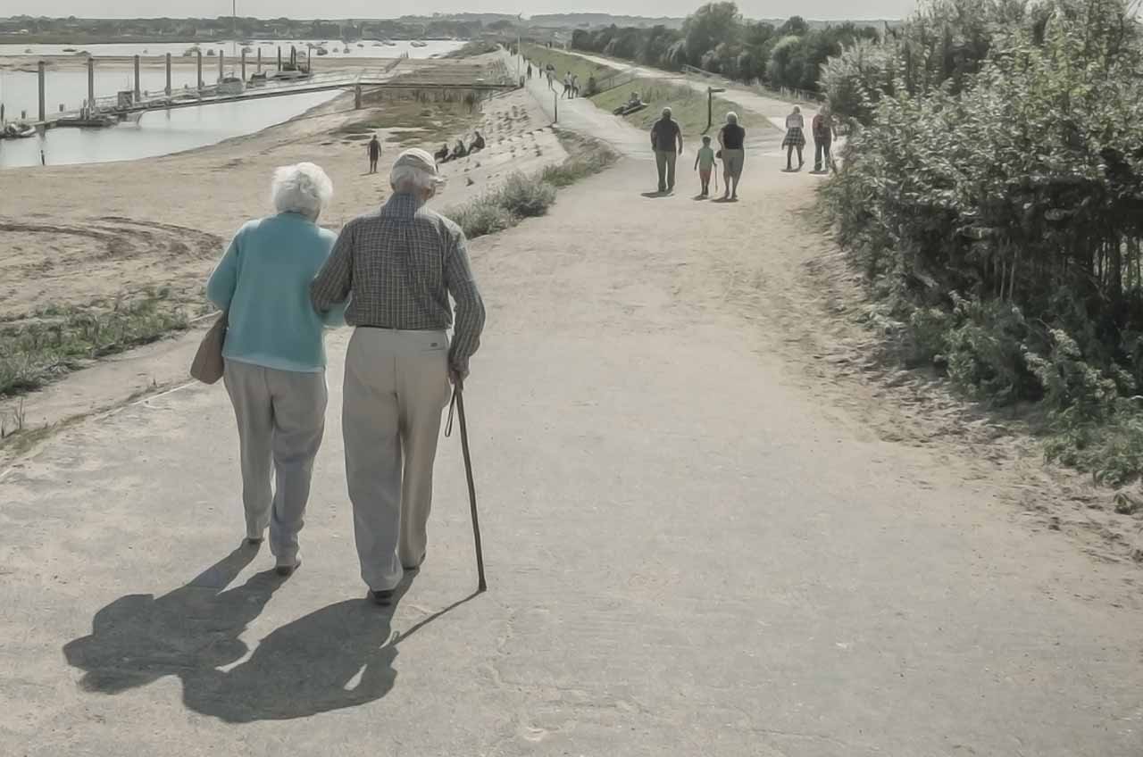 pareja de abuelos caminando y grupos de personas delante