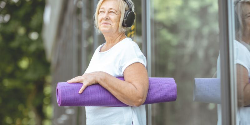 mujer adulta mayor con mat de yoga