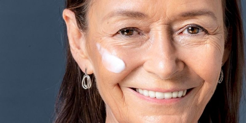 Mujer madura con un rastro de crema en la mejilla.
