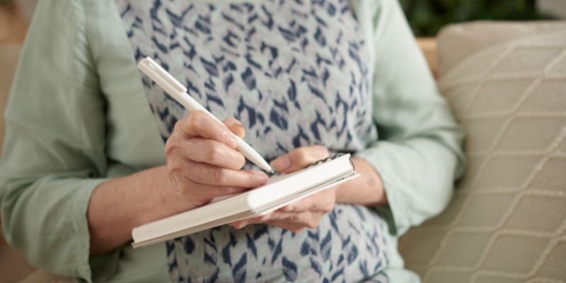 manos de mujer mayor anotando en una libreta